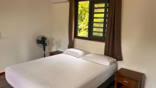 une chambre avec un lit blanc avec une fenêtre dans l'établissement HUAHINE- Fare Arc-en-Ciel, à Parea