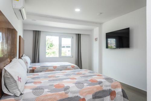 Un dormitorio con una cama y un televisor. en Hotel Suites Gaby, en Cancún