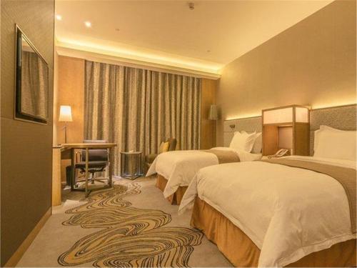 a hotel room with two beds and a desk at The Summit Hotel in Zhongshan