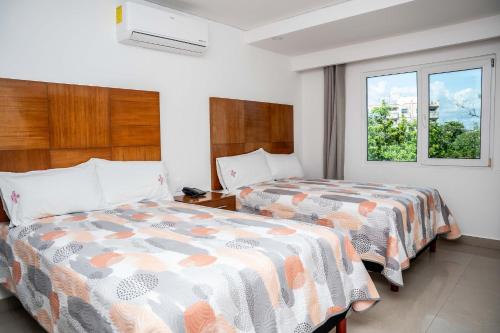 a bedroom with two beds and a window at Suites Gaby Cancun in Cancún