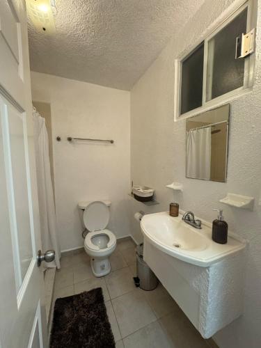 a white bathroom with a toilet and a sink at Departamento en Marina Diamante Rooftop y Jacuzzi privado in Acapulco