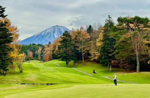 a man standing on a golf course with a mountain in the background at Private Villa ietona in Fujikawaguchiko