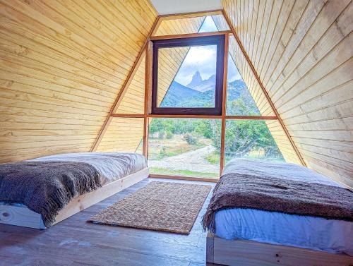 OUTSCAPE l Preciosa Cabaña en Villa Castillo في فيلا سيرو كاستيلو: سريرين في غرفة ذات نافذة كبيرة