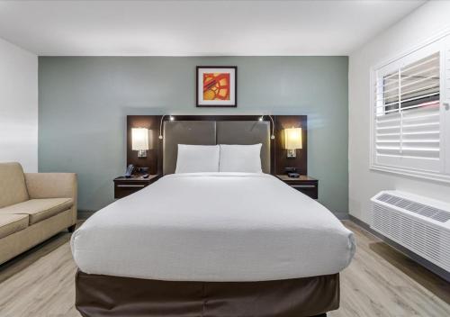 a bedroom with a large bed and a couch at Steinbeck Lodge in Salinas