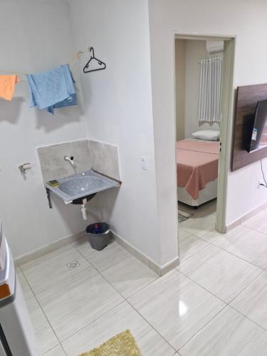 a bathroom with a sink and a room with a bed at Hospedagem do Elias in Cuiabá