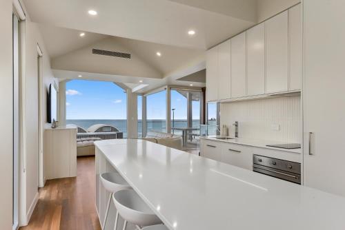 a kitchen with white cabinets and a view of the ocean at Aloha Beachfront Port Fairy in Port Fairy