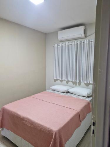 a bedroom with a bed with a pink blanket at Hospedagem do Elias in Cuiabá