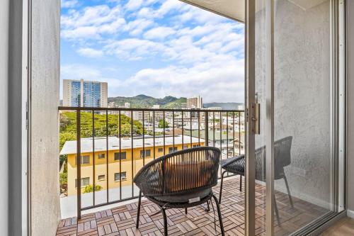 einen Balkon mit 2 Stühlen und Blick auf ein Gebäude in der Unterkunft Peaceful Modern HNL Getaway in Honolulu