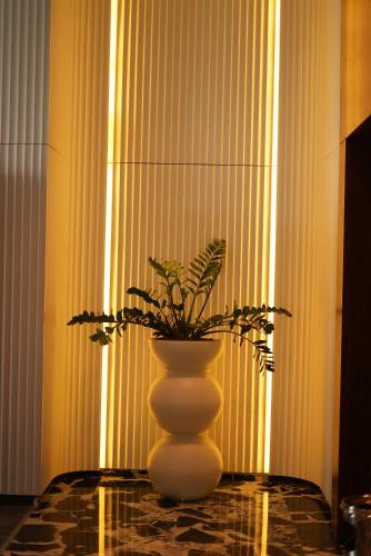 a white vase sitting on a table with a plant in it at Z Hotel Sfax in Sfax