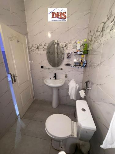 a white bathroom with a toilet and a sink at DHSimmo Cozy home in Rufisque