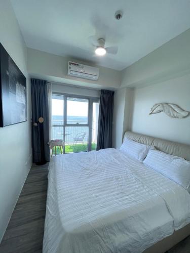 ein Schlafzimmer mit einem großen weißen Bett und einem Fenster in der Unterkunft 95 Sqm Flawless Seaview Luxurious Modern 2 Bedrooms Facing Manila Bay Sunset, Airports, Okada, Solaire, MOA with free parking in Manila