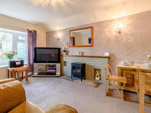 a living room with a fireplace and a television at Lilac Studio in Wheldrake