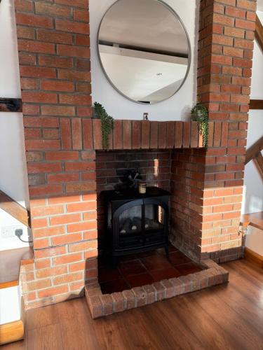 une cheminée en briques avec un miroir au-dessus dans l'établissement Slaymaker Cottage, à Oakworth