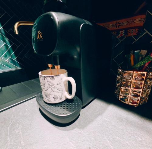 a coffee maker with a cup on a stand at La Bulle de Velours in Bouguenais
