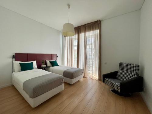 a bedroom with two beds and a chair and a window at Lisboa Arroios Apartment in Lisbon