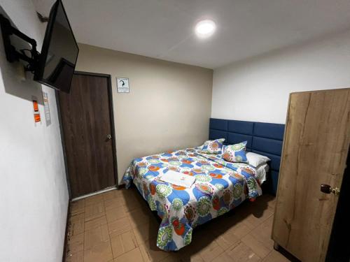 a bedroom with a bed and a flat screen tv at Hotel Inkanta in Nariño
