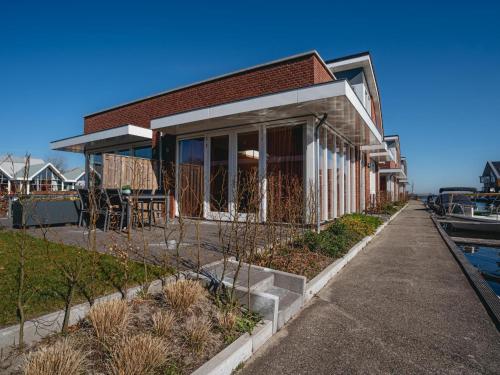 a house on the water with a sidewalk at Lakehouse I in Uitgeest