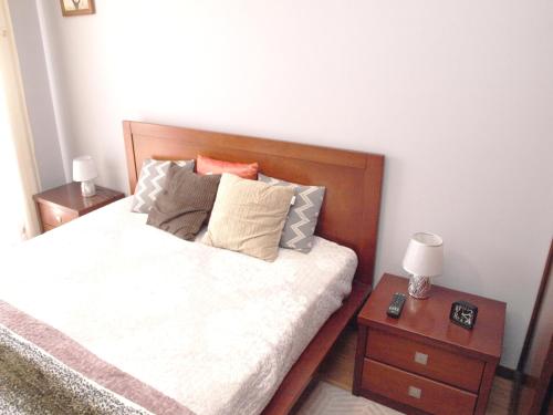 a bed with a wooden headboard and a night stand at EPS53 T1,luminoso apartamento, 800m praia Apulia in Apúlia