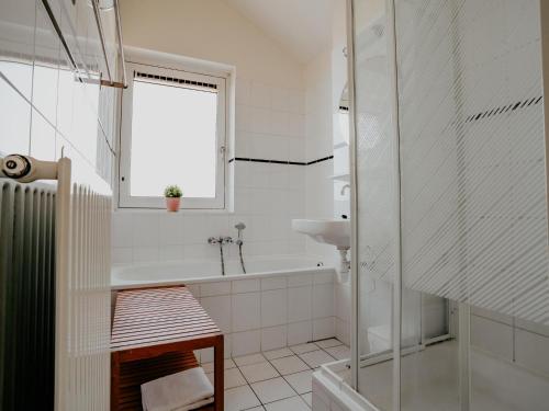 a white bathroom with a tub and a sink at Busch en Dam in Uitgeest