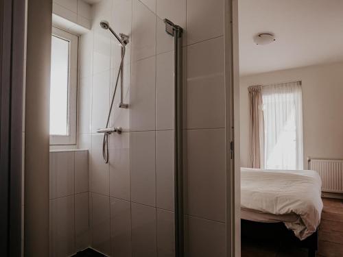 a bathroom with a shower and a bed at Waterbase in Uitgeest