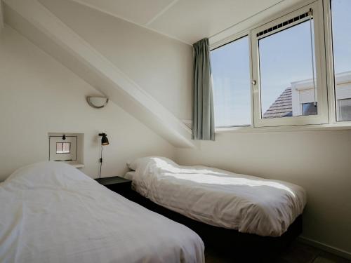 two beds in a room with a window at Oostergeest in Uitgeest