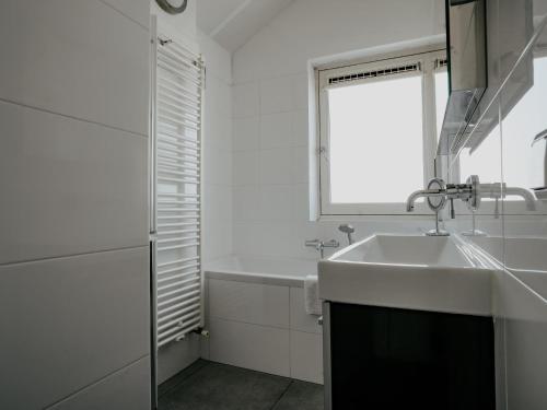 a white bathroom with a sink and a window at Dorregeest in Uitgeest
