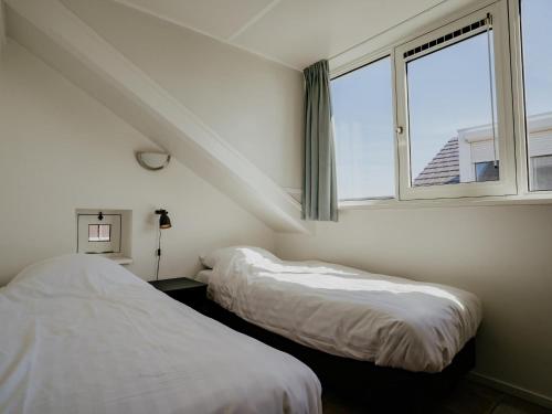 two beds in a room with a window at Dorregeest in Uitgeest