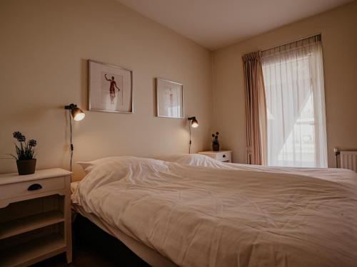 a bedroom with a white bed and a window at Waterbase in Uitgeest