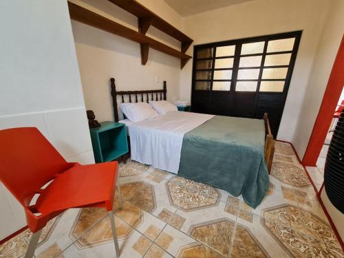 Un dormitorio con una cama y una silla roja. en Villa Pachamama Hospedaria - Praia do Rosa, en Praia do Rosa