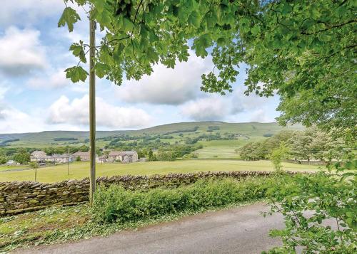 a road leading to a field with a stone wall at Bainbridge Ings in Hawes