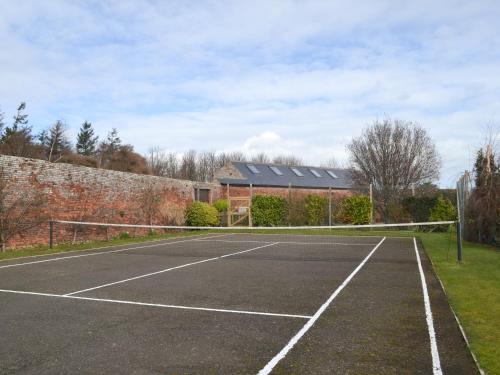 a tennis court in front of a building at The Granary Cottage in Warenford