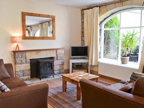 a living room with a fireplace and a television at The Granary Cottage in Warenford