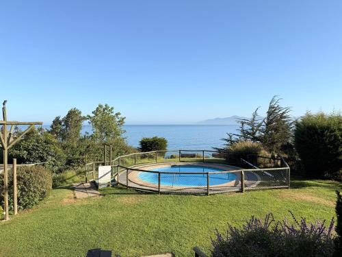 a swimming pool in a yard next to the water at Departamento B84 in Puchuncaví