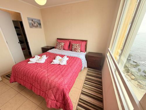 a bedroom with a red bed with two white flowers on it at Departamento B84 in Puchuncaví