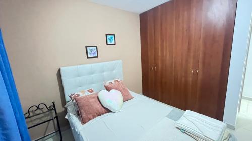 a bedroom with a white bed with a wooden cabinet at Habitación dentro de un Apartamento compartido in Ibagué