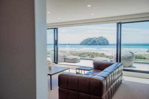 a living room with a couch and a large window at Belle Mer Beachfront Apartments in Mount Maunganui