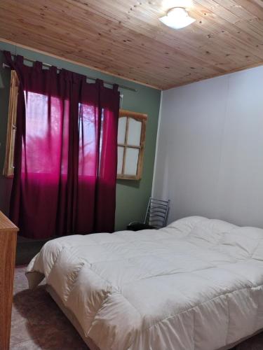 Cabaña El Maturrango的卧室配有白色的床和红色窗帘
