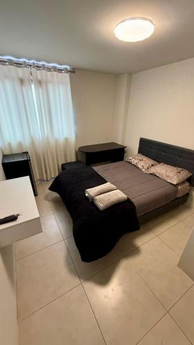 a bedroom with a black bed and a table at Habitación Matrimonial en el centro de la ciudad in Ayacucho