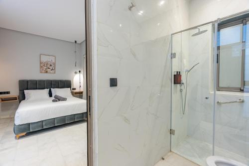 une salle de bain avec une douche en verre et un lit dans l'établissement Faya Nova- Appart hotel Central Stay, à Casablanca