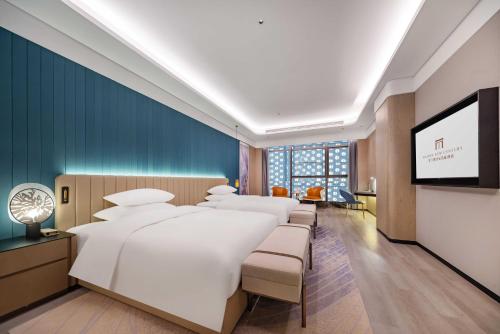 fila de camas en una habitación con TV de pantalla plana en Jiujiang Fanglan Lake Kaiyuan Mingting Hotel, 