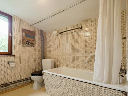 a bathroom with a bath tub and a toilet at Rustic Retreat in Houvegné in Houvegné