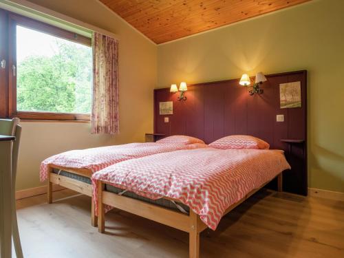 two beds in a bedroom with a window at Rustic Retreat in Houvegné in Houvegné