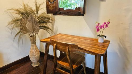 a wooden table and a vase with flowers on it at Ananda B&B in Gili Air
