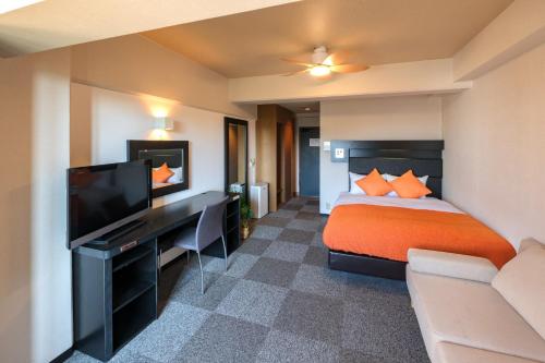 Cette chambre comprend un lit et un bureau avec une télévision. dans l'établissement Miyazaki Mango Hotel - Vacation STAY 58252v, à Miyazaki