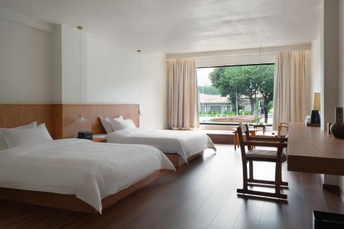 a bedroom with two beds and a desk and a window at Quanzhou Wuji Homestay in Quanzhou