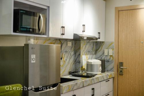 eine Küche mit weißen Schränken und einem silbernen Kühlschrank in der Unterkunft Condo in Marilao Bulacan at Cheer Residence in Marilao