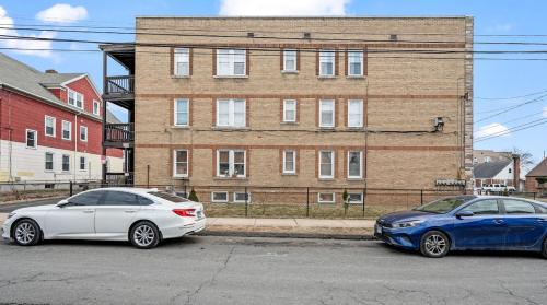 two cars parked in a parking lot in front of a building at Downtown Hartford 2BR Family Pet Friendly in Hartford