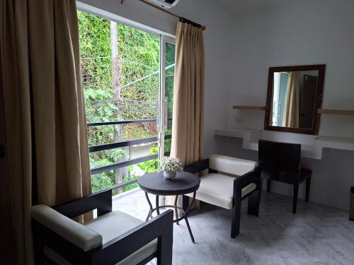 a living room with a table and chairs and a window at Suwita House in Nai Yang Beach
