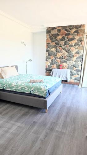 a bedroom with a bed and a stone wall at room near train station and airport in Perth