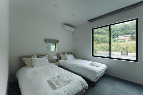 zwei Betten in einem Zimmer mit großem Fenster in der Unterkunft Laf Denen 千葉県富津市のvacation rental in Futtsu